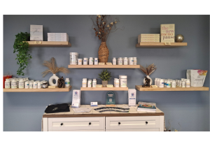 Harmony Hormone Solutions - A display of wellness supplements and books on floating shelves above a white cabinet, with decorative plants and informational brochures arranged neatly.